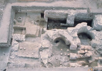 Vue aérienne de fouilles archéologiques, montrant des structures antiques en pierre partiellement dégagées