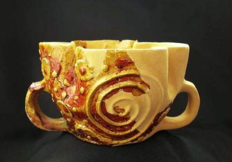 Vase ancien décoré de motifs en relief représentant des volutes et des anses latérales, typique de l'artisanat du moyen âge classique.